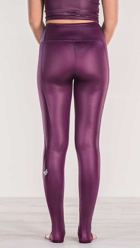 Close up rear view of model wearing shiny eggplant purple colored full length leggings with right side pocket