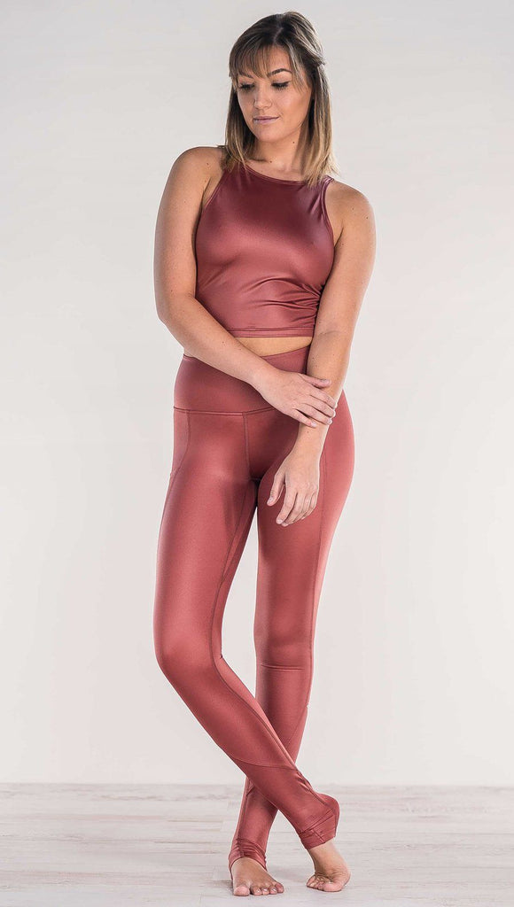 Front view of model crossing ankles wearing shiny mauve full length leggings with right side pocket