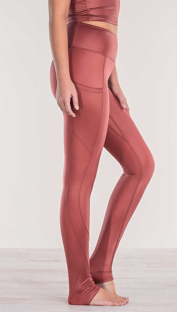 Close up side view of model wearing shiny mauve full length leggings with right side pocket