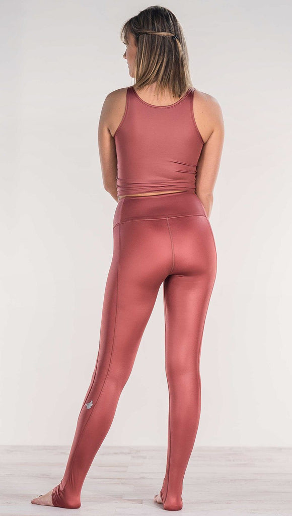 Rear view of model wearing shiny mauve full length leggings with right side pocket