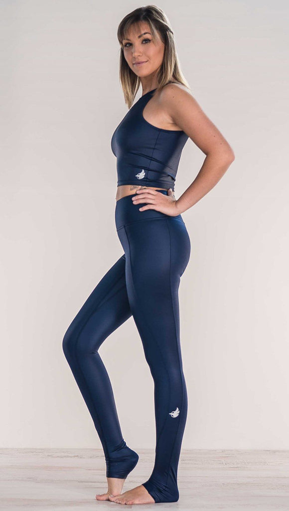 Side view of model wearing shiny midnight blue full length leggings with right side pocket