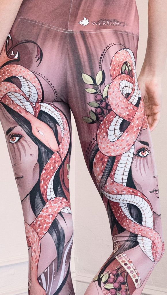 Zoomed in back view of the model wearing full length athleisure leggings with a mauve color medusa head and red, white, and black snakes