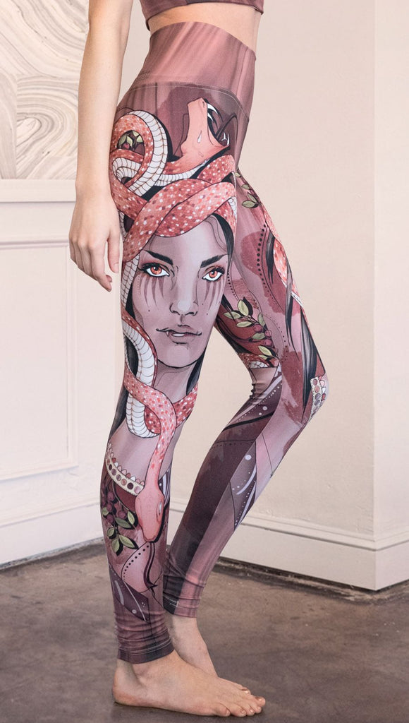 Right side view of the model wearing full length athleisure leggings with a mauve color medusa head and red, white, and black snakes