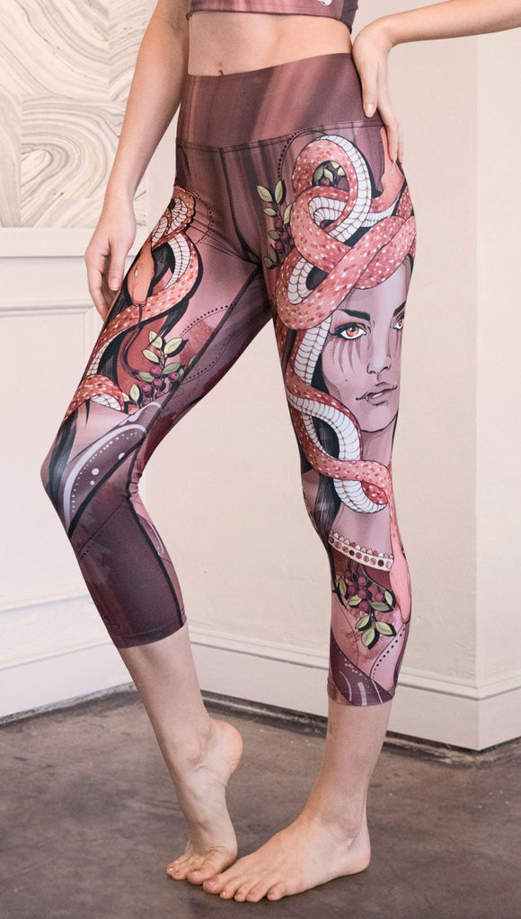 Left view of model wearing capri leggings with a mauve color medusa head and red, white, and black snakes