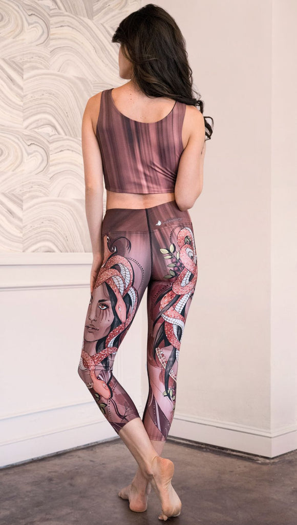 Back view of model wearing capri leggings with a mauve color medusa head and red, white, and black snakes