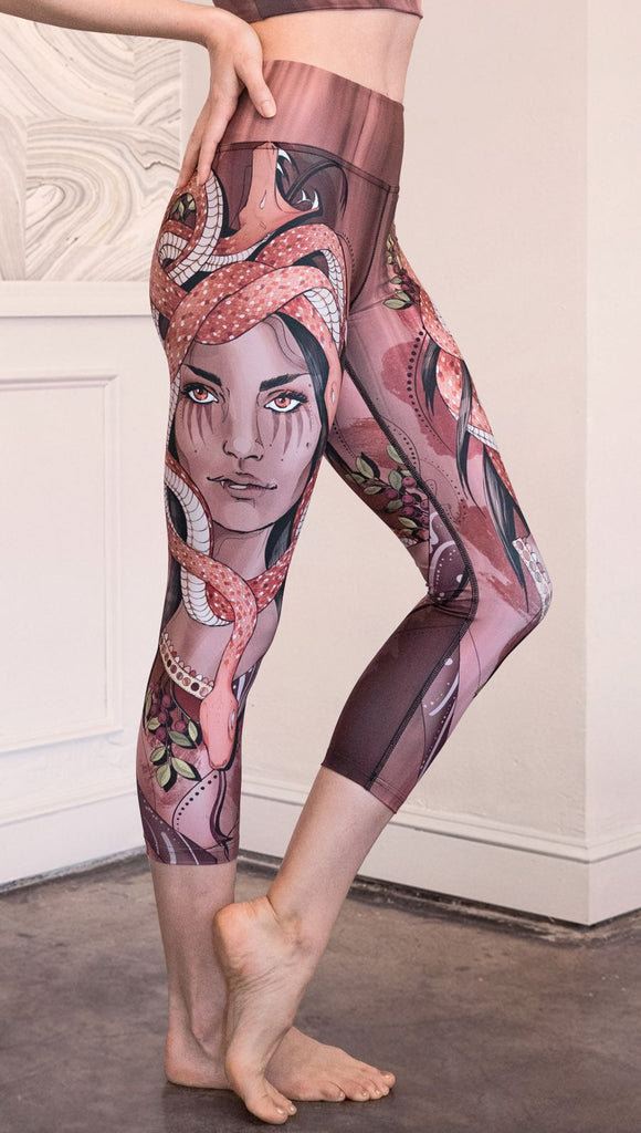 Right side view of model wearing capri leggings with a mauve color medusa head and red, white, and black snakes