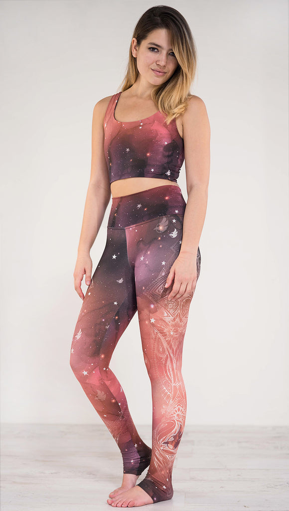 Left side view of model wearing a red, orange and purple galaxy themed athleisure leggings with white henna inspired art running along the left side of the leg