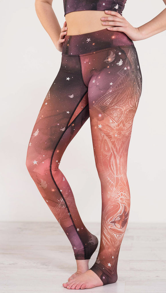 Left side view of model wearing a red, orange and purple galaxy themed triathlon leggings with white henna inspired art running along the left side of the leg