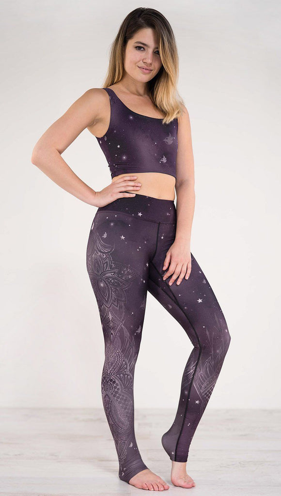 Right side view of model wearing purple galaxy themed triathlon leggings with white henna inspired flowers running along the right side of the leg