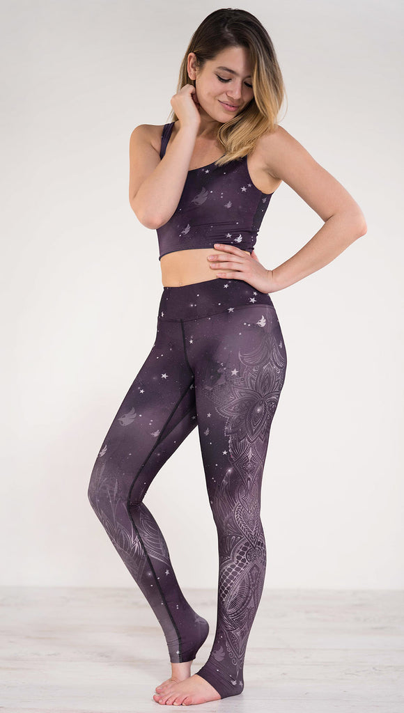 Left side view of model wearing purple galaxy themed triathlon leggings with white henna inspired flowers running along the left side of the leg