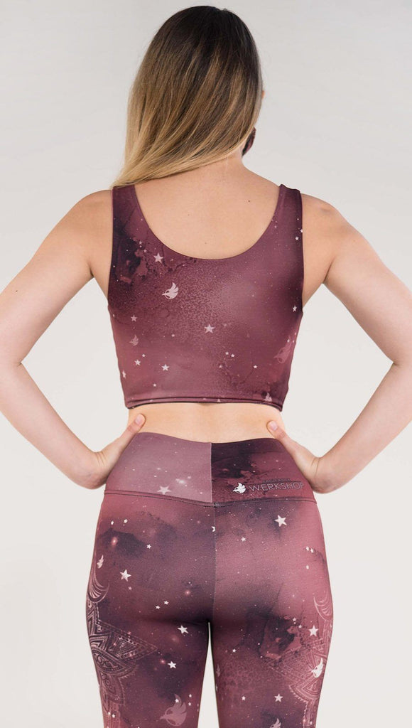 Back side view of model wearing a merlot color galaxy themed reversible crop top called Galactic Merlot on this side