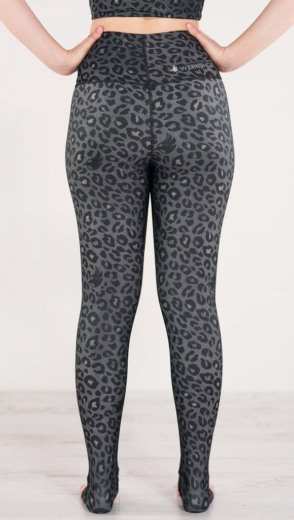 Back side view of model wearing the reversible charcoal leopard print athleisure leggings in the colors gray and black