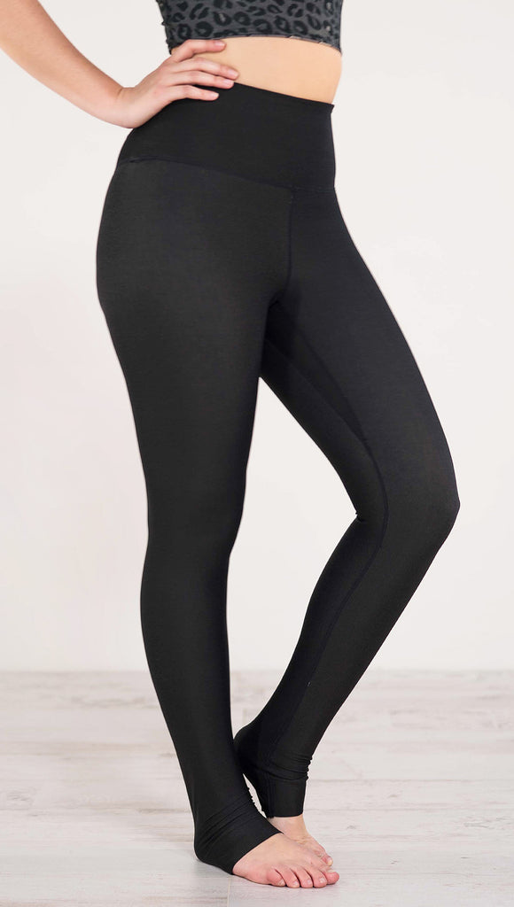Right side view of model wearing reversible charcoal leopard athleisure leggings in the reversed all black side showing 