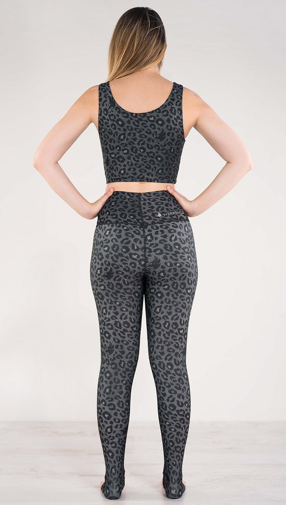 Back side view of model wearing the reversible charcoal leopard print athleisure leggings in the colors gray and black