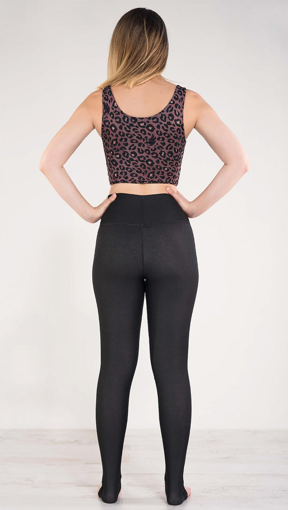 Back side view of model wearing the reversible red leopard athleisure leggings in the reversed all black side showing