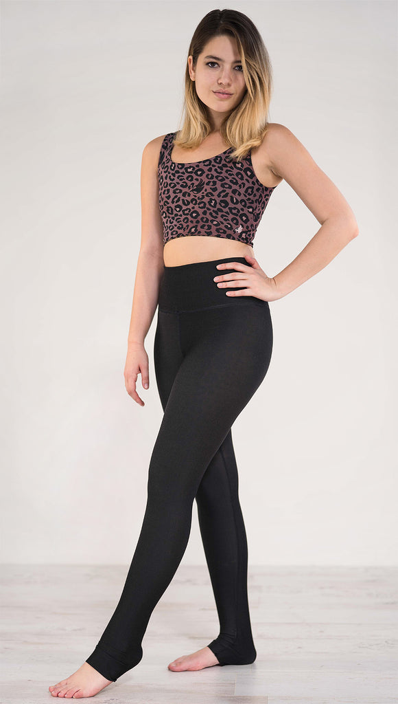 Left side view of model wearing the reversible red leopard athleisure leggings in the reversed all black side showing