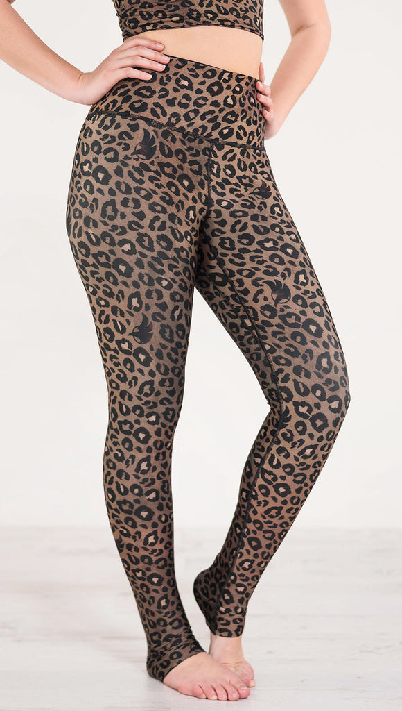 Right side view of model wearing the reversible tan leopard print athleisure leggings in the colors tan and black