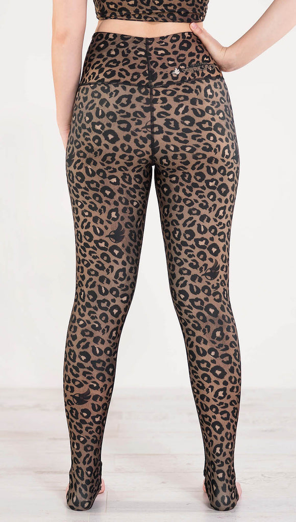 Back side view of model wearing the reversible tan leopard print athleisure leggings in the colors tan and black