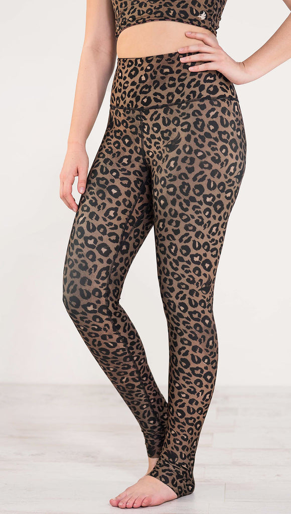 Left side view of model wearing the reversible tan leopard print athleisure leggings in the colors tan and black