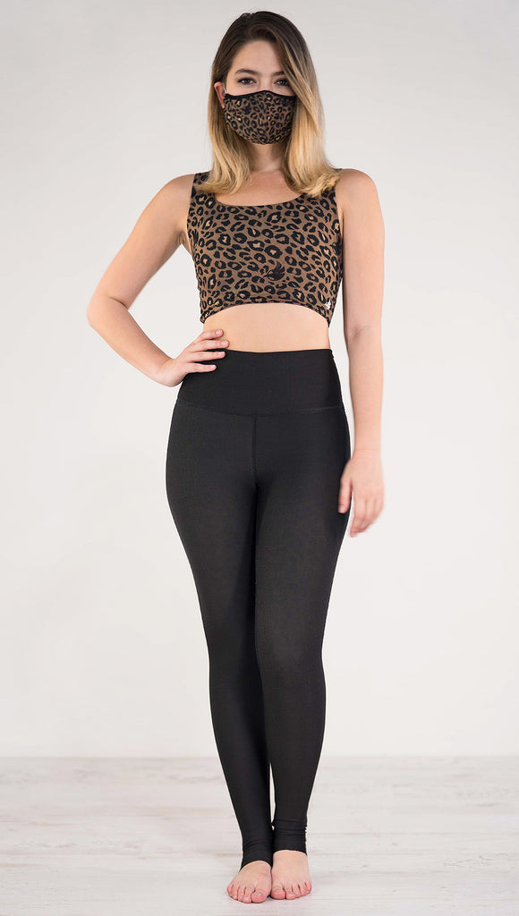 Front view of model wearing the reversible tan leopard athleisure leggings in the reversed all black side showing