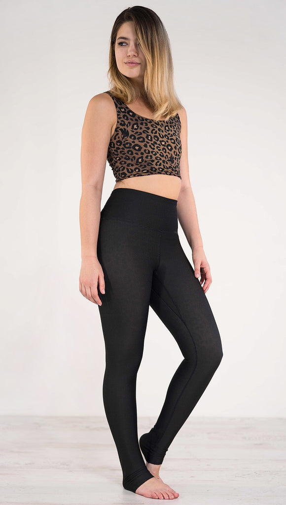 Right side view of model wearing the reversible tan leopard athleisure leggings in the reversed all black side showing