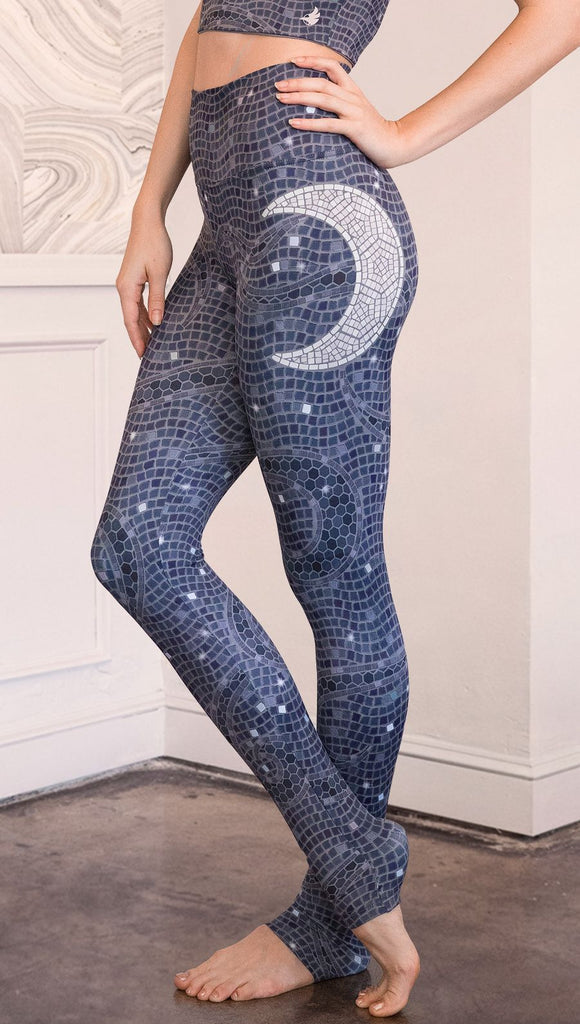 Close up left side view of model wearing mosaic printed full length leggings with moon artwork on left hip