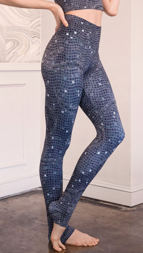 Close up right side view of model wearing mosaic printed full length leggings with moon artwork on left hip
