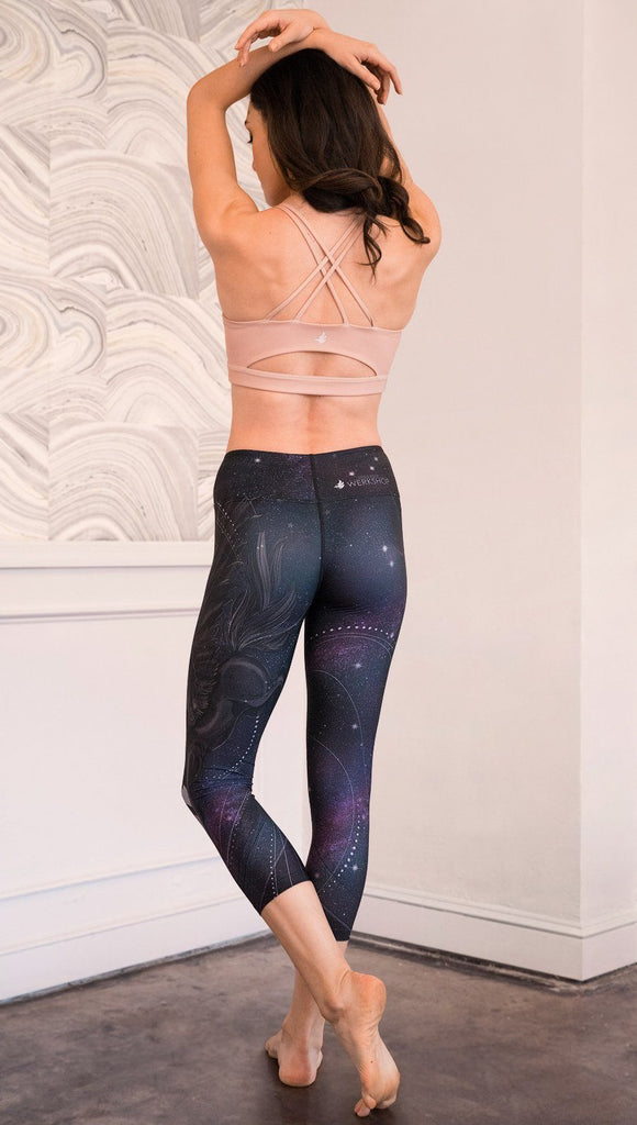 back view of model wearing fantasy flying pegasus themed printed capri leggings