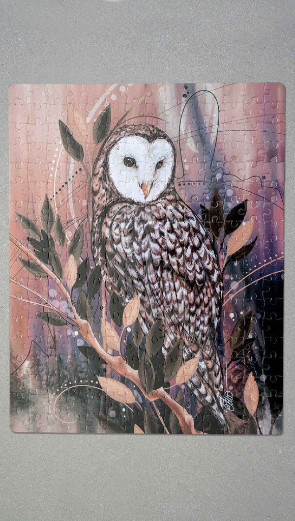 WERKSHOP Barn Owl252 piece jigsaw puzzle. The puzzle is printed with original artwork of an Owl by Chriztina Marie. It features a barn owl perched on top of a branch with whimsical leaves. The overall color story is of mauves, warm browns and complimentary green leaves. 