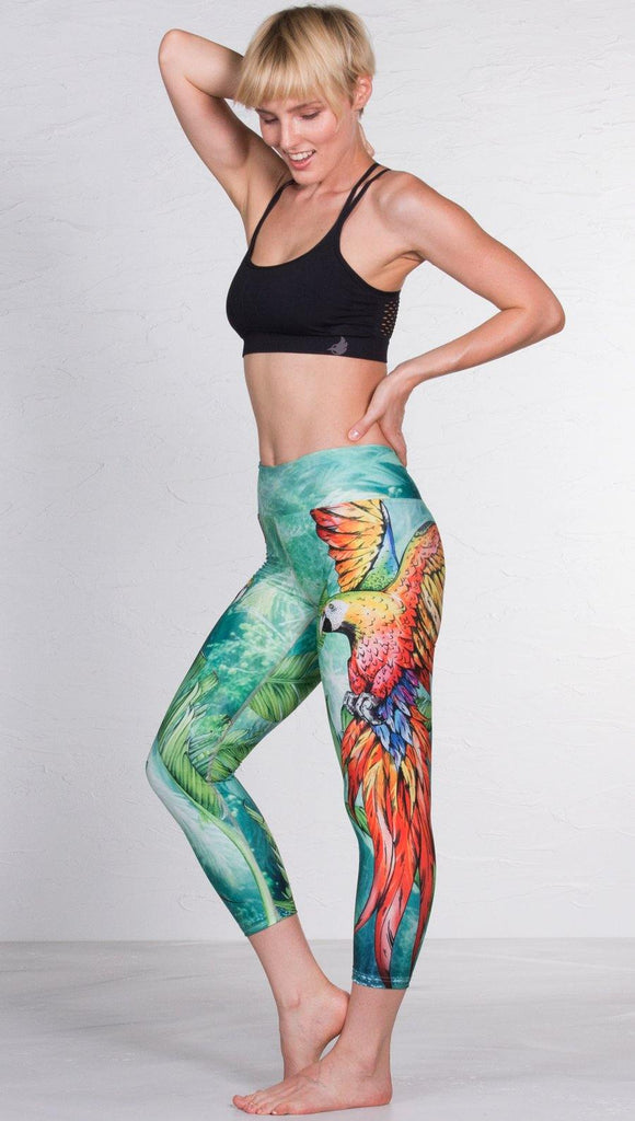 left side view of model wearing macaw themed capri leggings