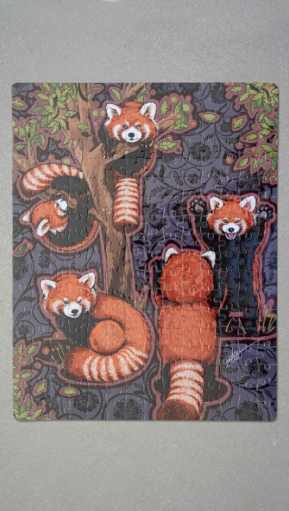 WERKSHOP Red Pandas Puzzle. The artwork features 5 adorable red pandas playing near an abstract tree with a warm gray background.