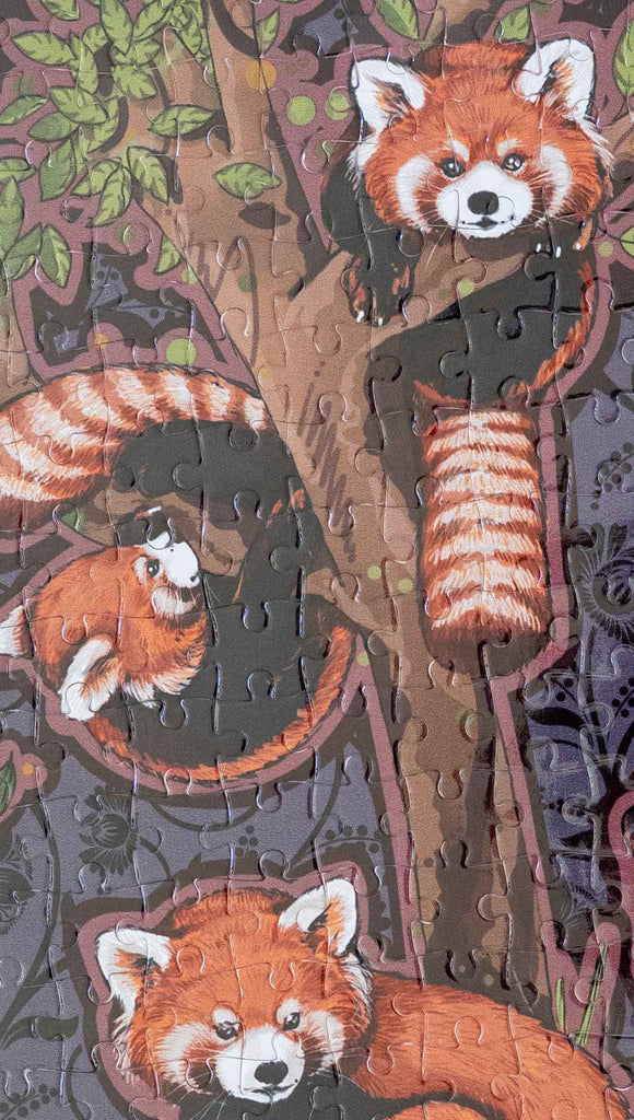 Zoomed in view of WERKSHOP Red Pandas Puzzle. The artwork features 5 adorable red pandas playing near an abstract tree with a warm gray background.