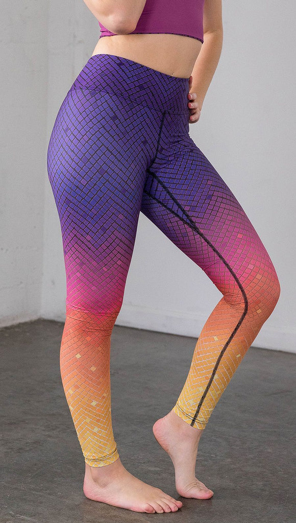 close up right side view of a model wearing purple/pink/yellow ombre mosaic tile print full length leggings