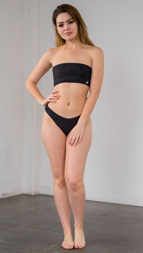 Front view of model wearing reversible bikini bottom with celestial galaxy print on one side and black leather texture print on the opposite side