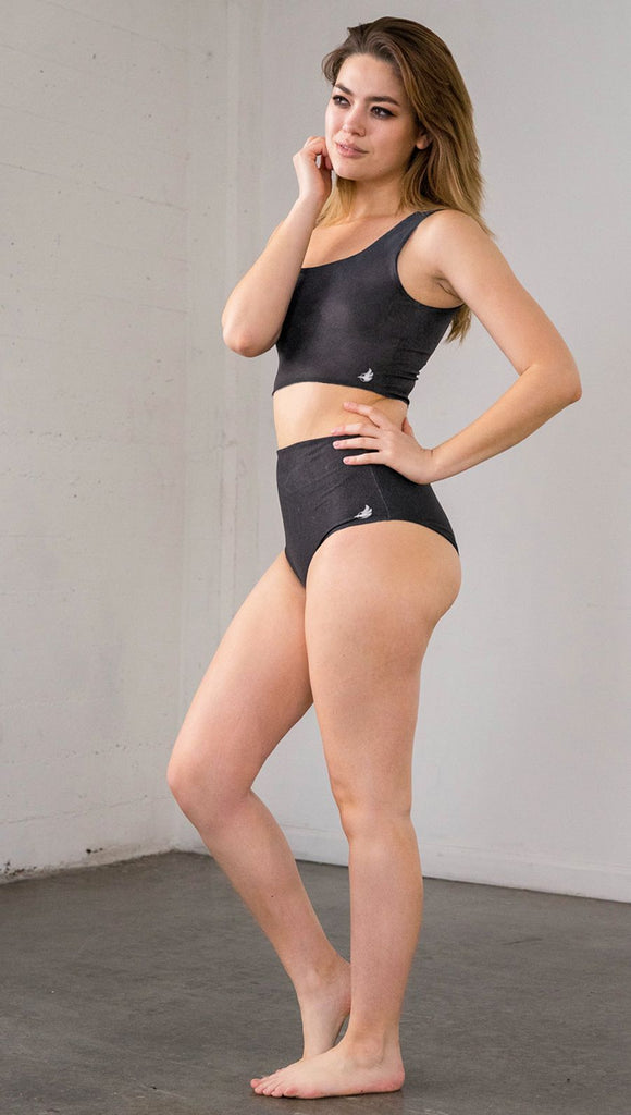 Left side view of model wearing reversible high-waist bikini bottom with celestial galaxy print on one side and black leather texture print on the opposite side