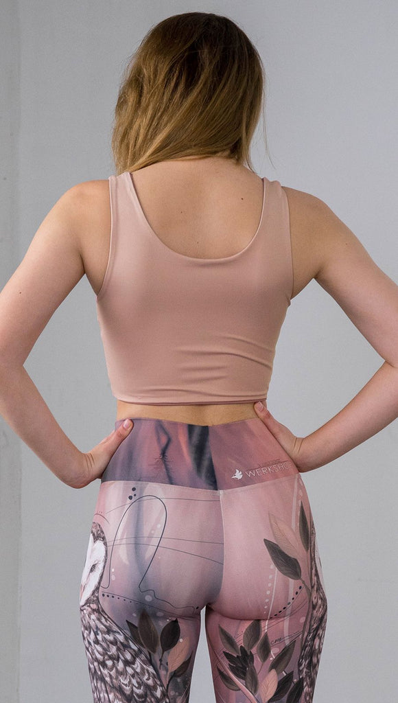 Three quarter length rear view of model wearing a reversible beige/light skin tone crop top with a light brown/medium skin top on the inside