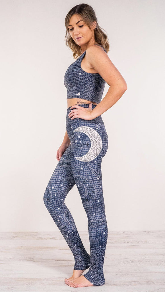 Left side view of model wearing mosaic printed full length leggings with moon artwork on left hip