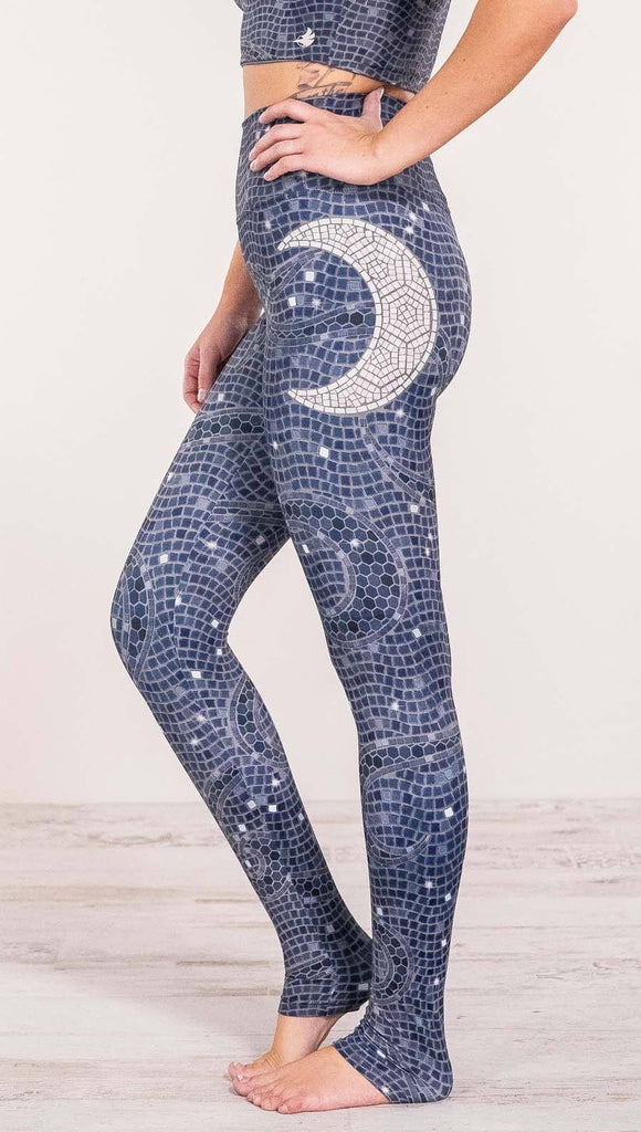 Close up left side view of model wearing mosaic printed full length leggings with moon artwork on left hip