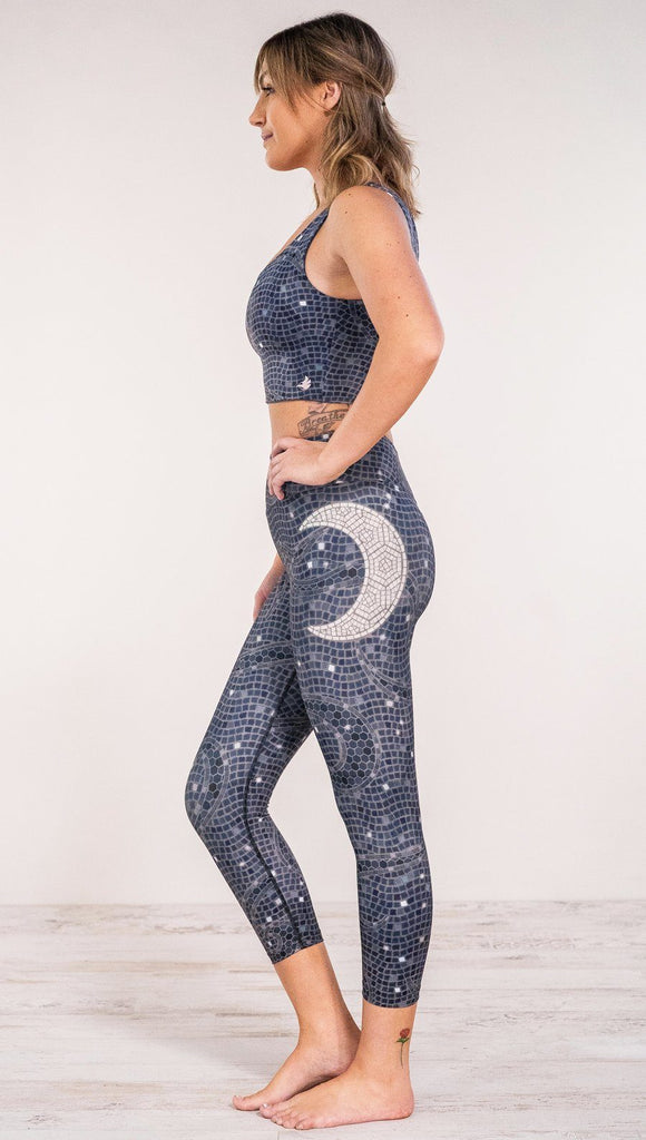 Left side view of model wearing mosaic printed capri leggings with moon artwork on left hip
