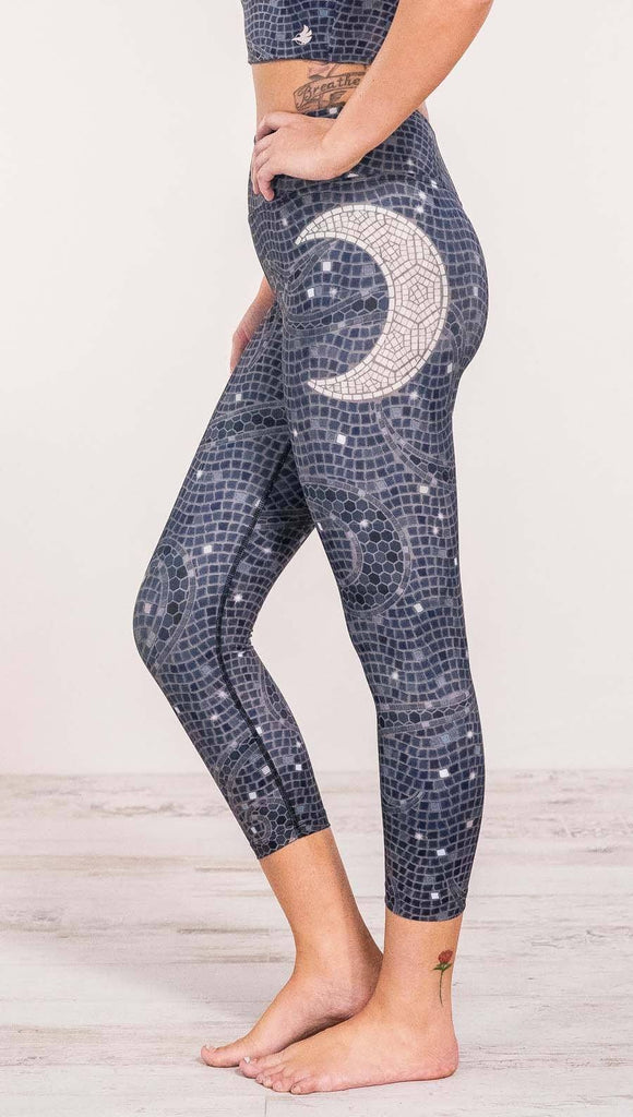Close up left side view of model wearing mosaic printed capri leggings with moon artwork on left hip