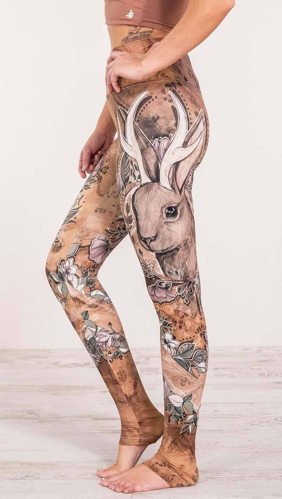 Close up left side view of model wearing full length leggings with printed jackalope design