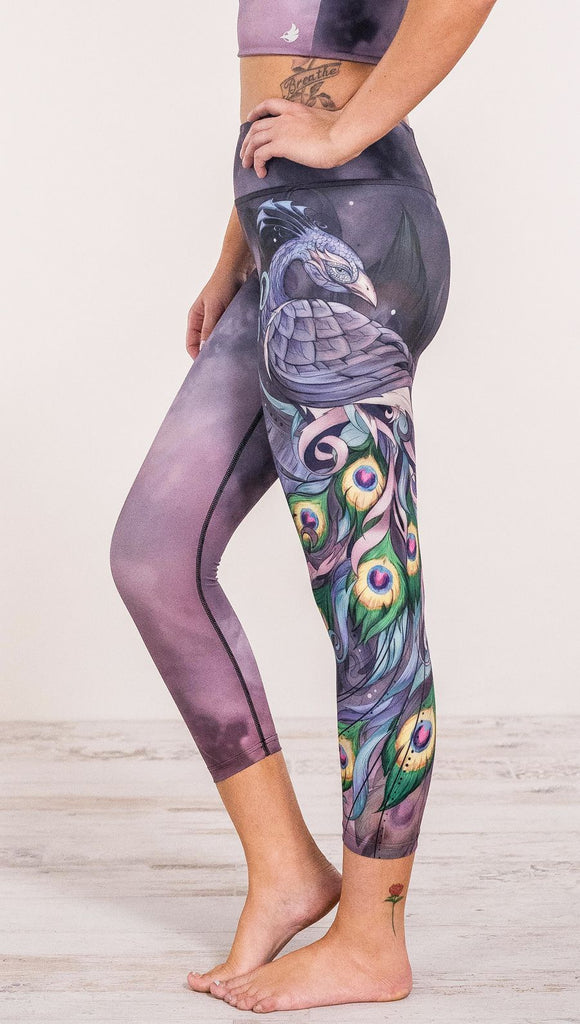 Close up side view of model wearing peacock themed leggings