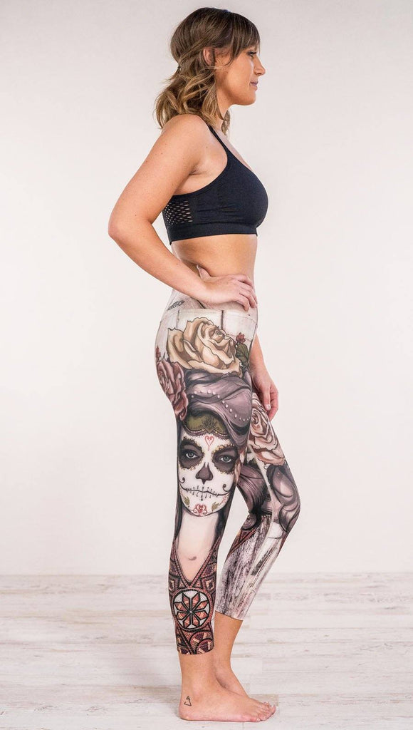 Right side view of model wearing sugar skull themed printed capri leggings