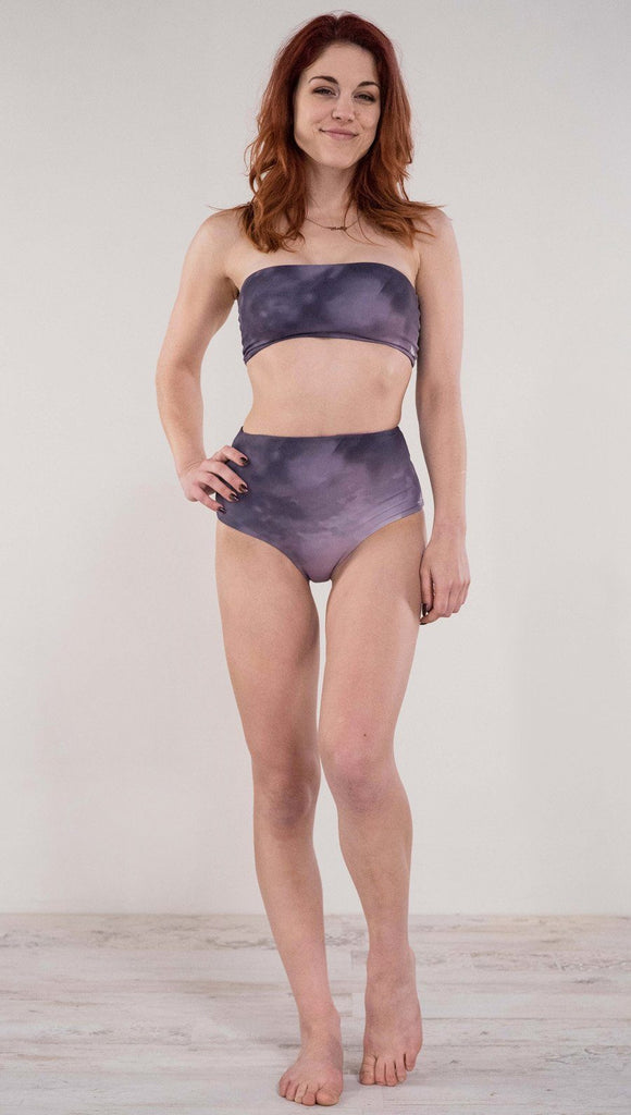 Front view of model wearing the reversible Peacock high waist bikini bottom in the Peacock side in the colors purple and dark purple