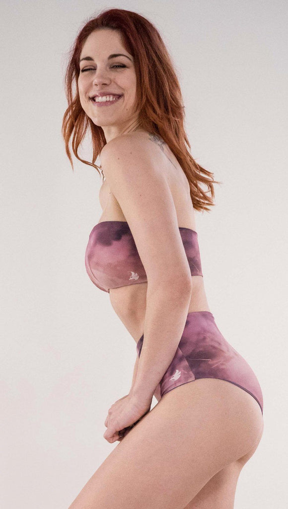 Left side view of model wearing the reversible Peacock high waist bikini bottom in the Rose Quartz side in the colors pink and purple