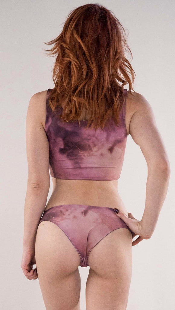 Back side view of model wearing the reversible Peacock low rise bikini bottom in the Rose Quartz side in the colors pink and purple