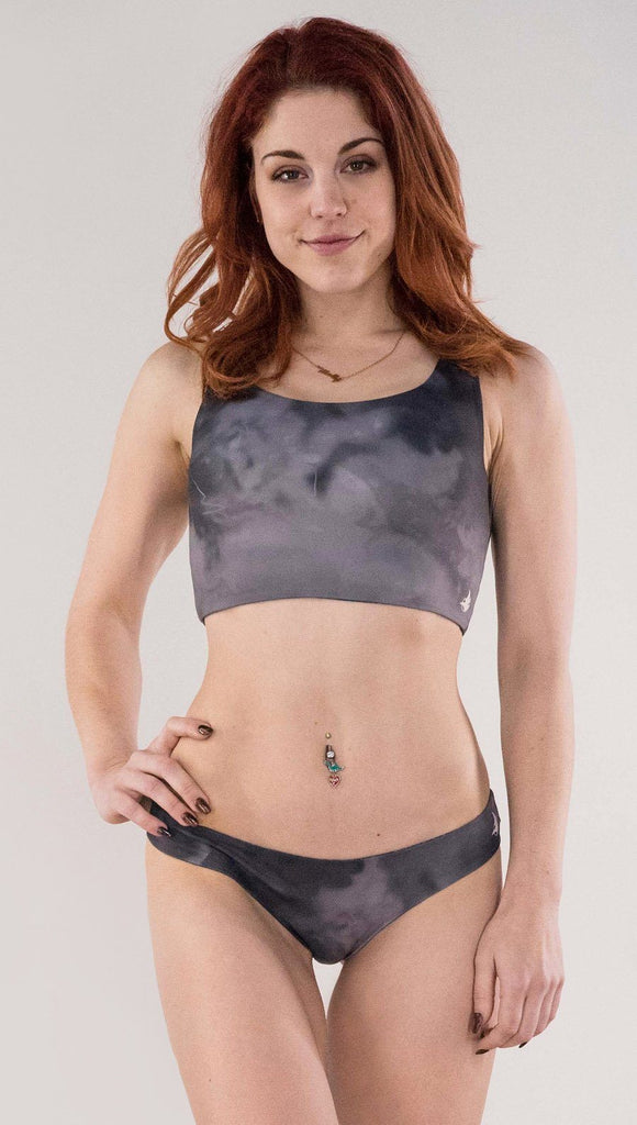 Front view of model wearing the reversible Celestial Mosaic low rise bikini bottom in the Smokey Quartz side in the colors gray and dark gray