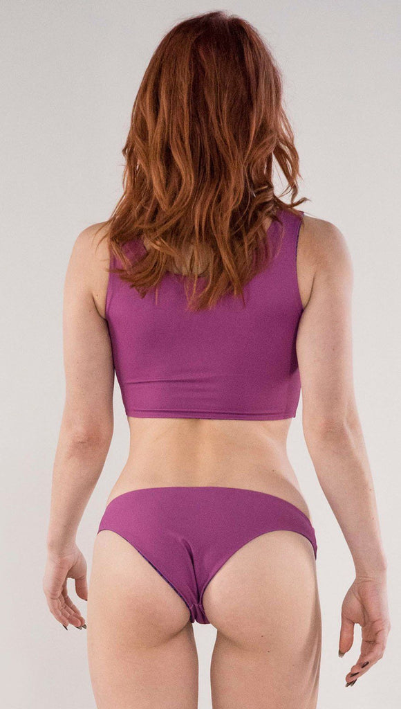 Back side view of model wearing the reversible Rainbow Mosaic low rise bikini bottom in the reversed fuchsia side