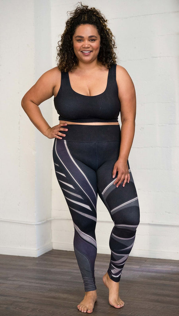 Front view of model wearing black printed full-length leggings with purple and gray stripe design