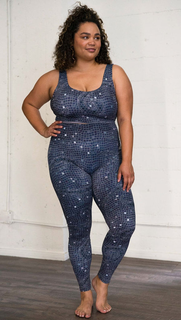 Front view of model wearing mosaic printed full length leggings with moon artwork on left hip
